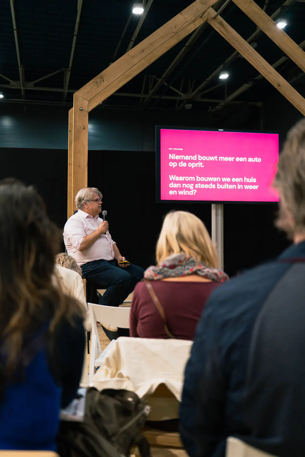 Bezoekers luisteren naar de lezing van eVilla. Op het scherm staat: Niemand bouwt meer een auto op de oprit.