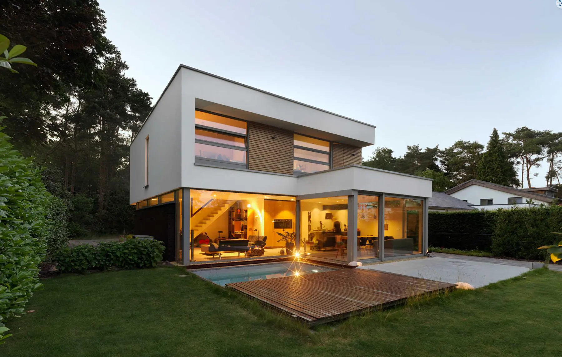 Moderne villa met wit stucwerk en hout, een glazen hoek en een terras aan de tuin
